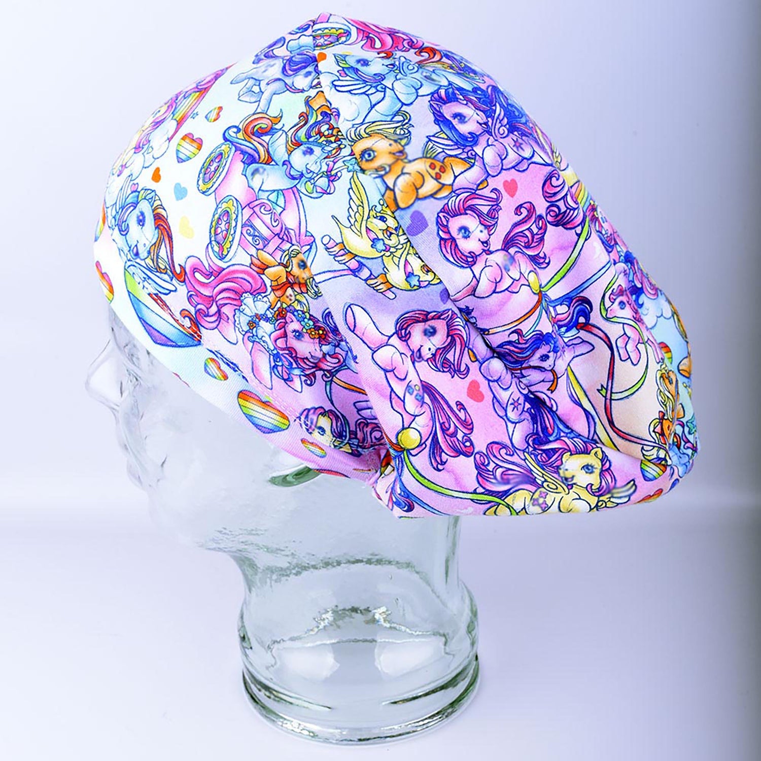 Full coverage scrub cap featuring the "Rainbow Ponies" pattern with colorful, whimsical ponies and rainbows on a light background.