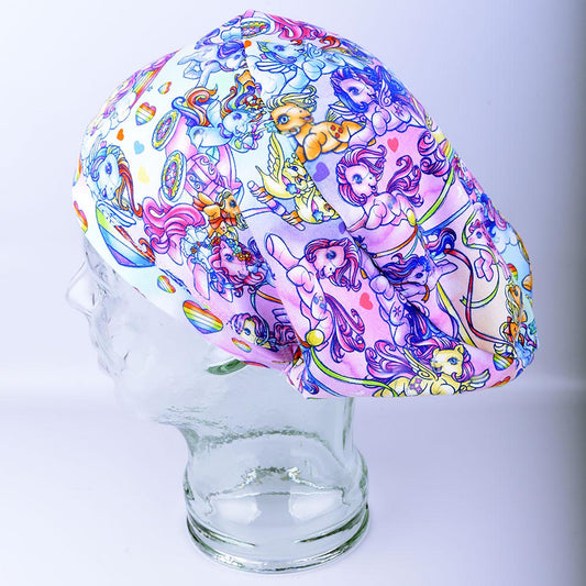 Full coverage scrub cap featuring the "Rainbow Ponies" pattern with colorful, whimsical ponies and rainbows on a light background.