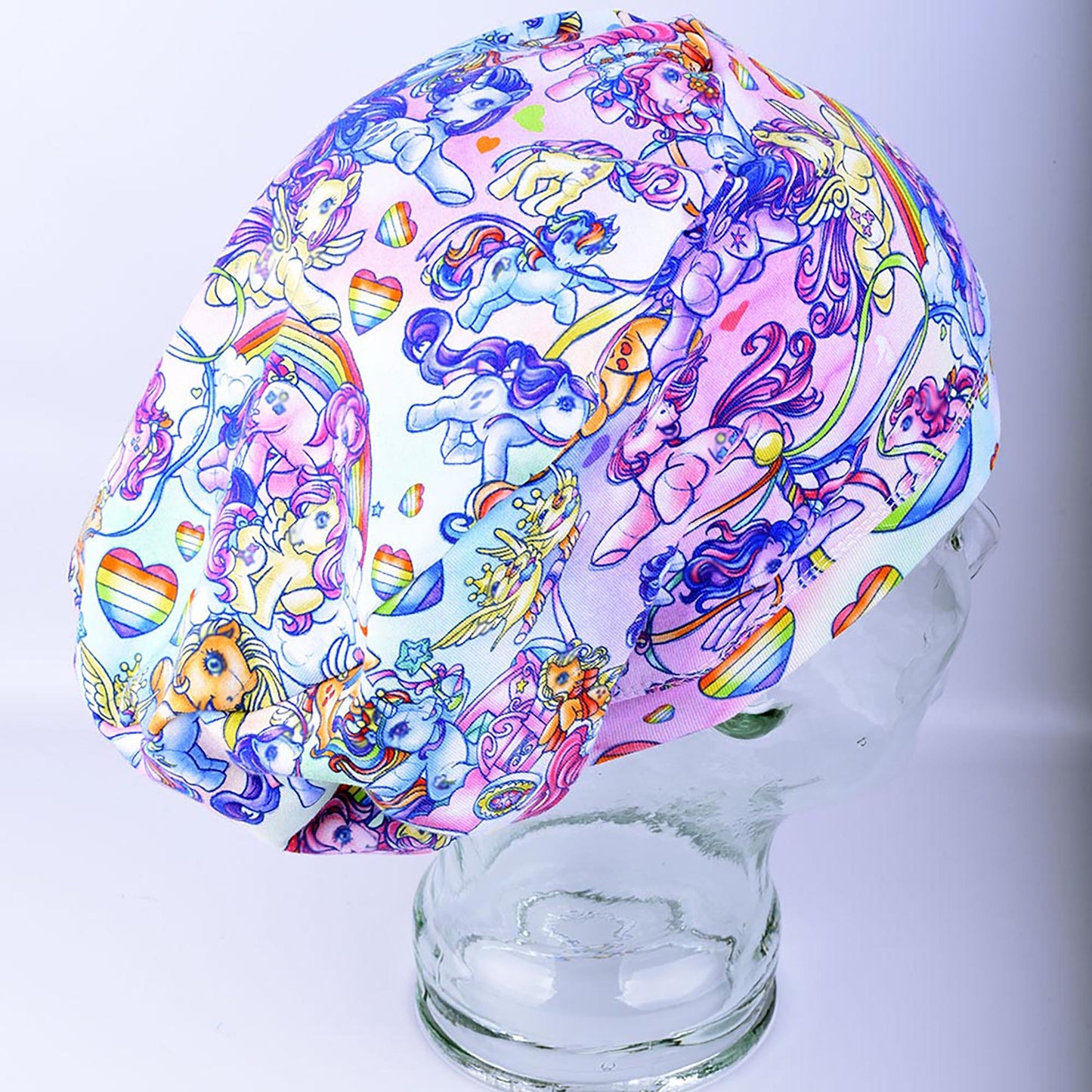 Full coverage scrub cap featuring the "Rainbow Ponies" pattern with colorful, whimsical ponies and rainbows on a light background.