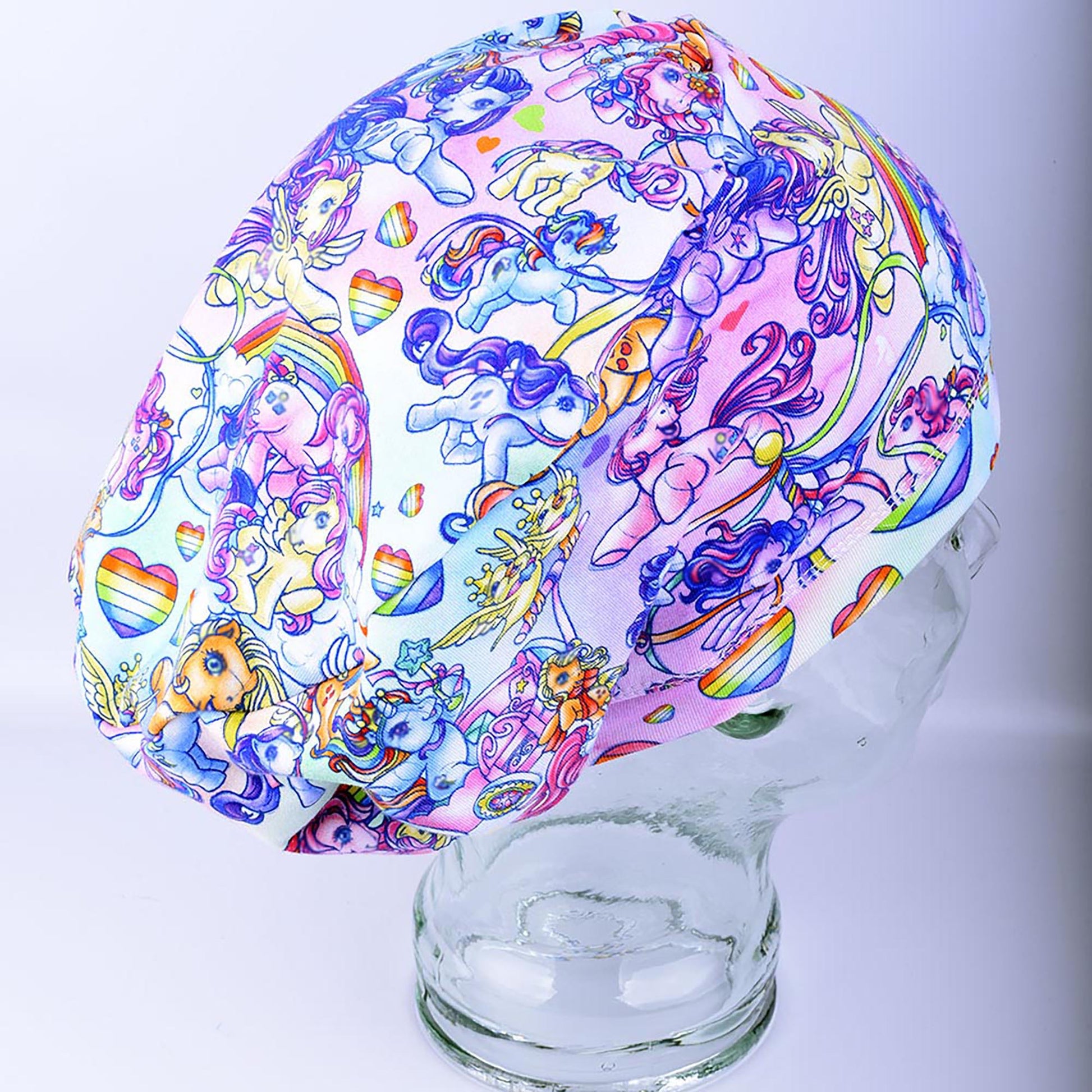 Full coverage scrub cap featuring the "Rainbow Ponies" pattern with colorful, whimsical ponies and rainbows on a light background.