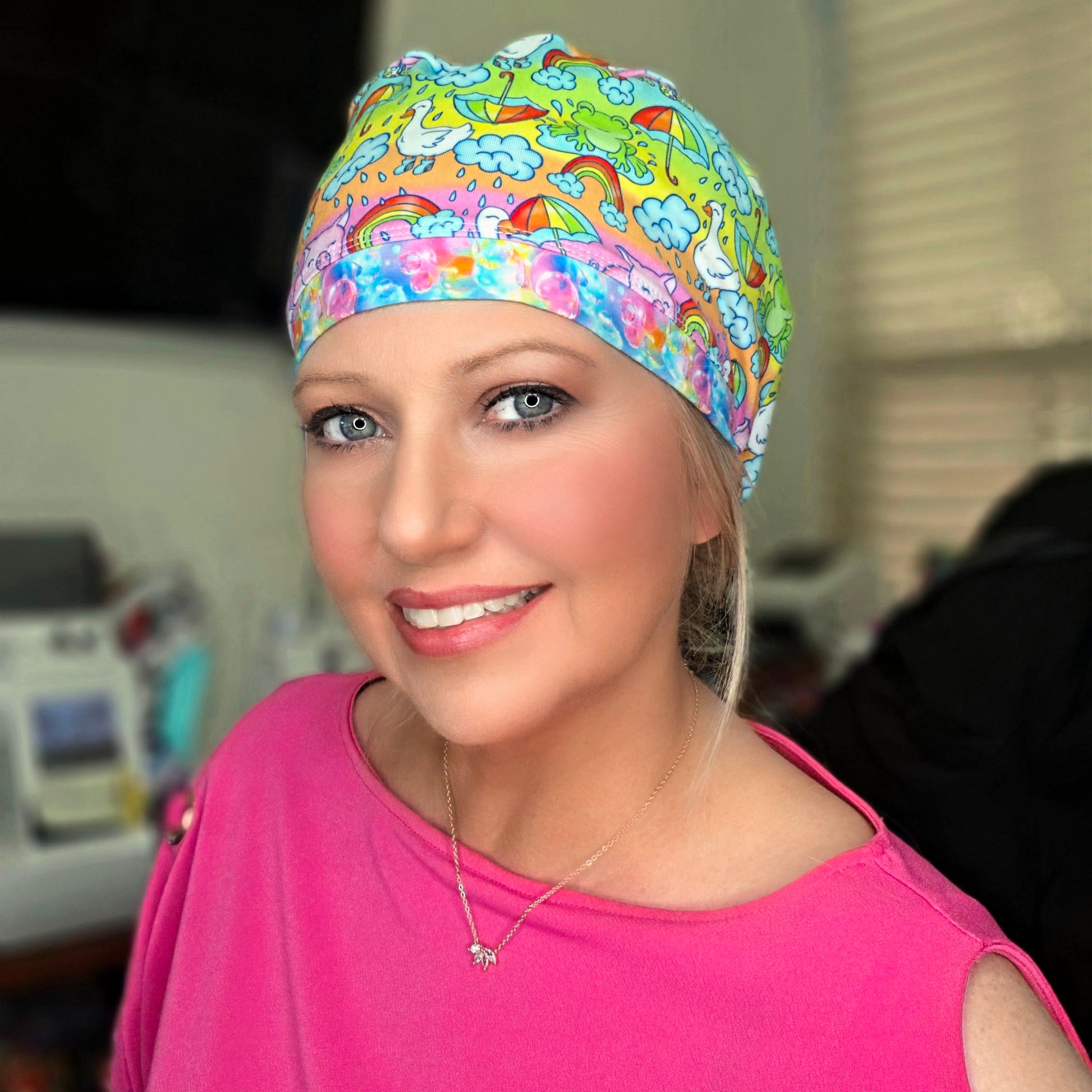 Female healthcare professional wearing the Raindrops and Rainbows stretch knit scrub cap with a pink top.