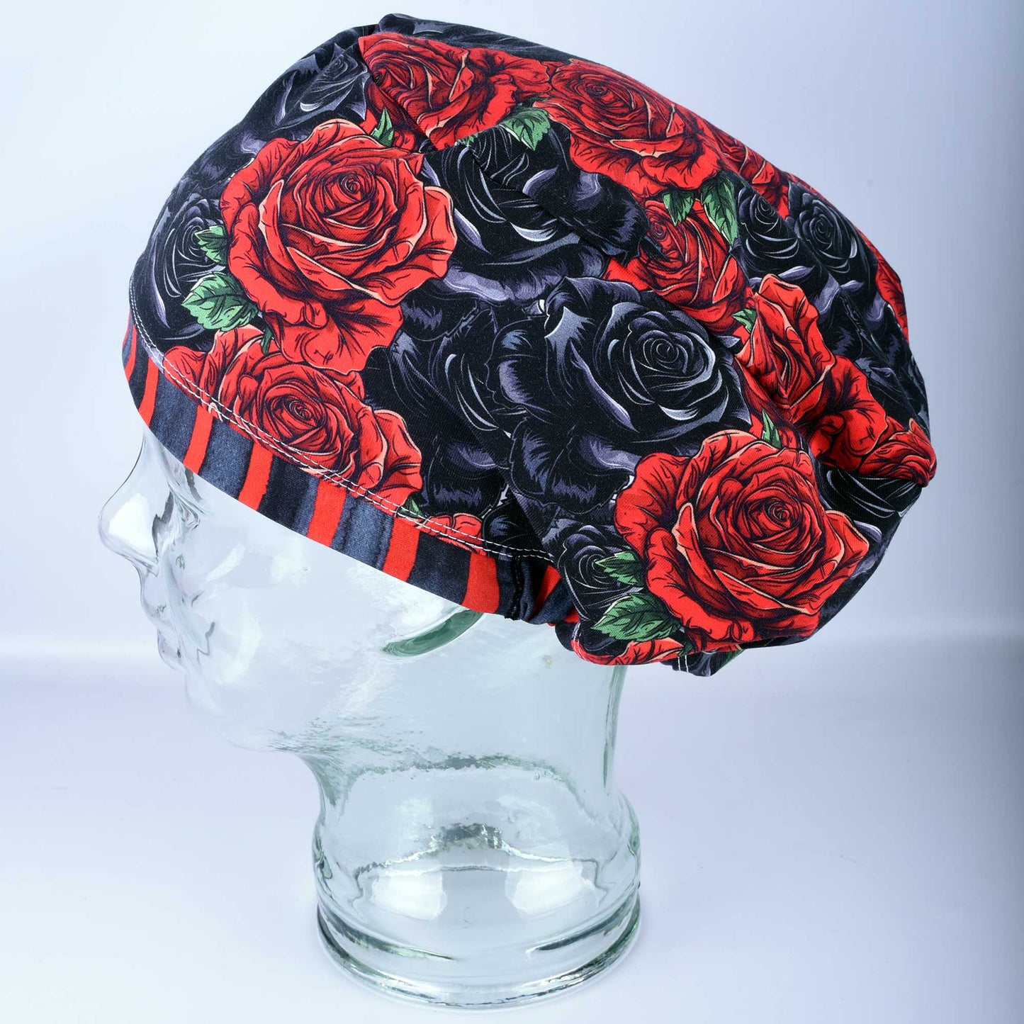 Full coverage scrub cap featuring a vibrant red and black rose floral pattern on a dark background, shown from a side profile to highlight the adjustable fit.