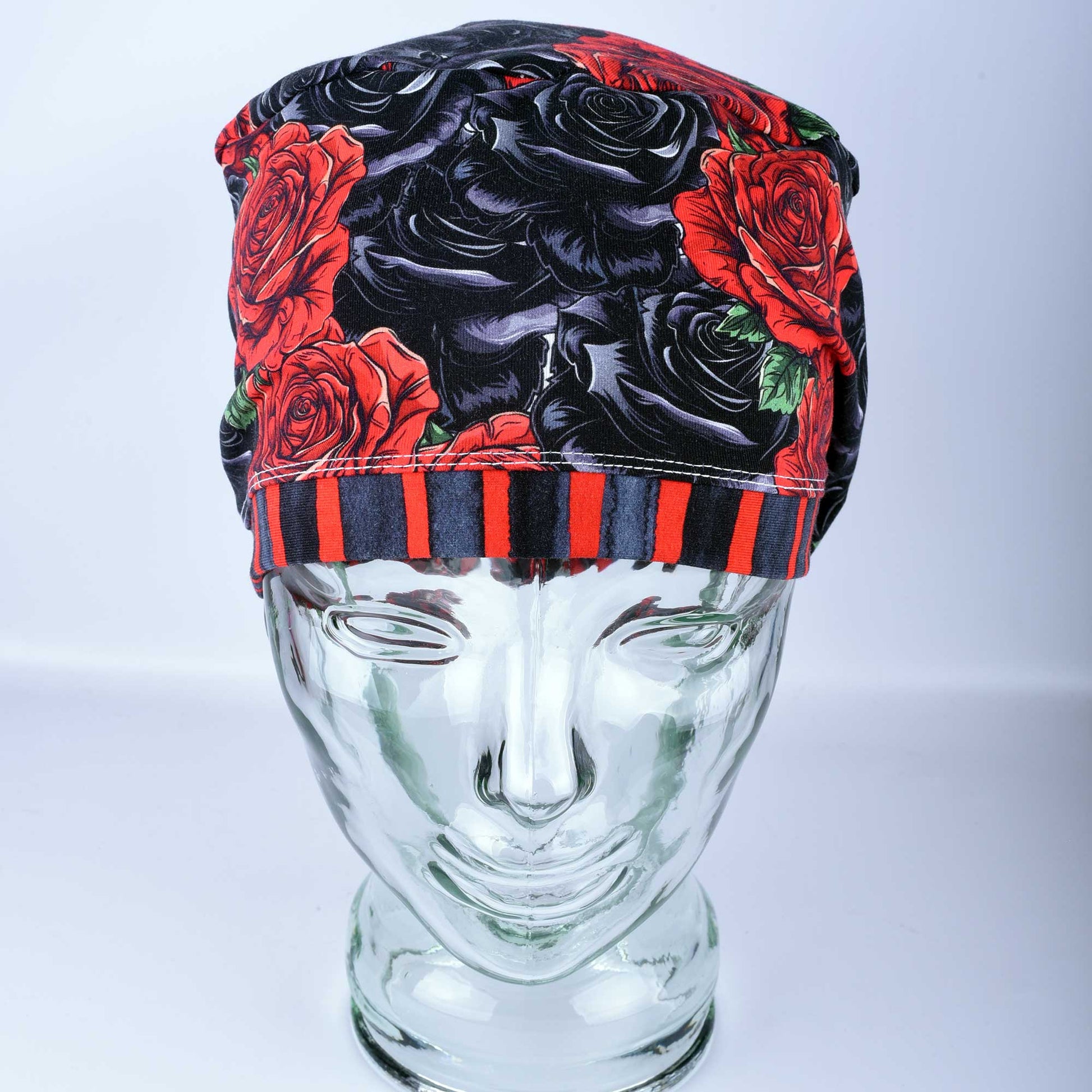 Full coverage scrub cap featuring a vibrant red and black rose floral pattern on a dark background, shown from a side profile to highlight the adjustable fit.