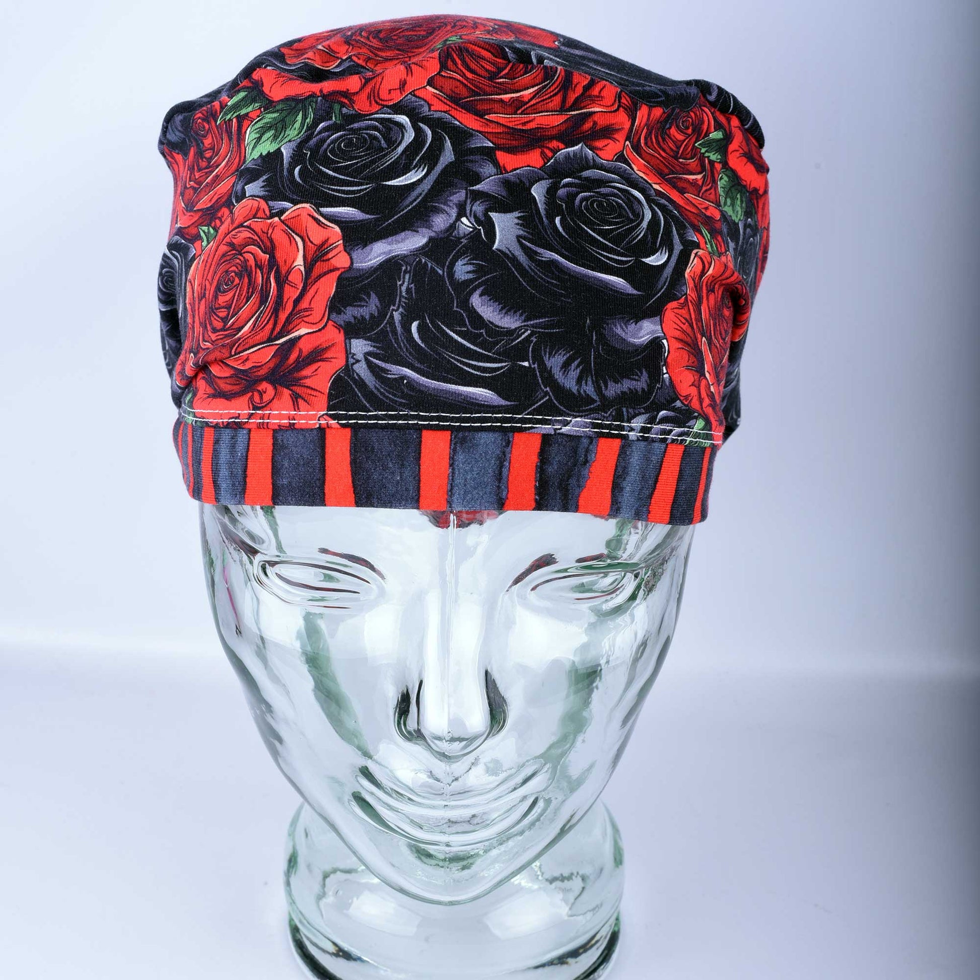 Full coverage scrub cap featuring a vibrant red and black rose floral pattern on a dark background, shown from a side profile to highlight the adjustable fit.