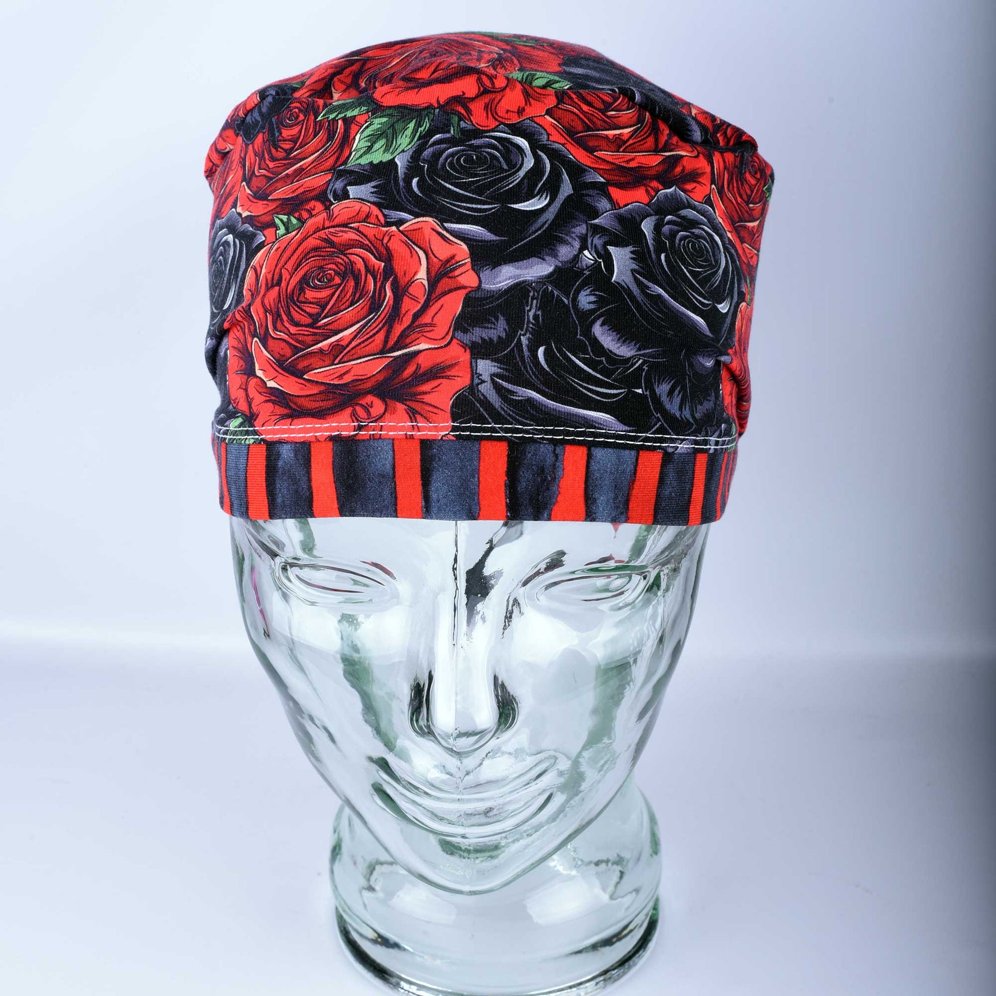 Full coverage scrub cap featuring a vibrant red and black rose floral pattern on a dark background, shown from a side profile to highlight the adjustable fit.