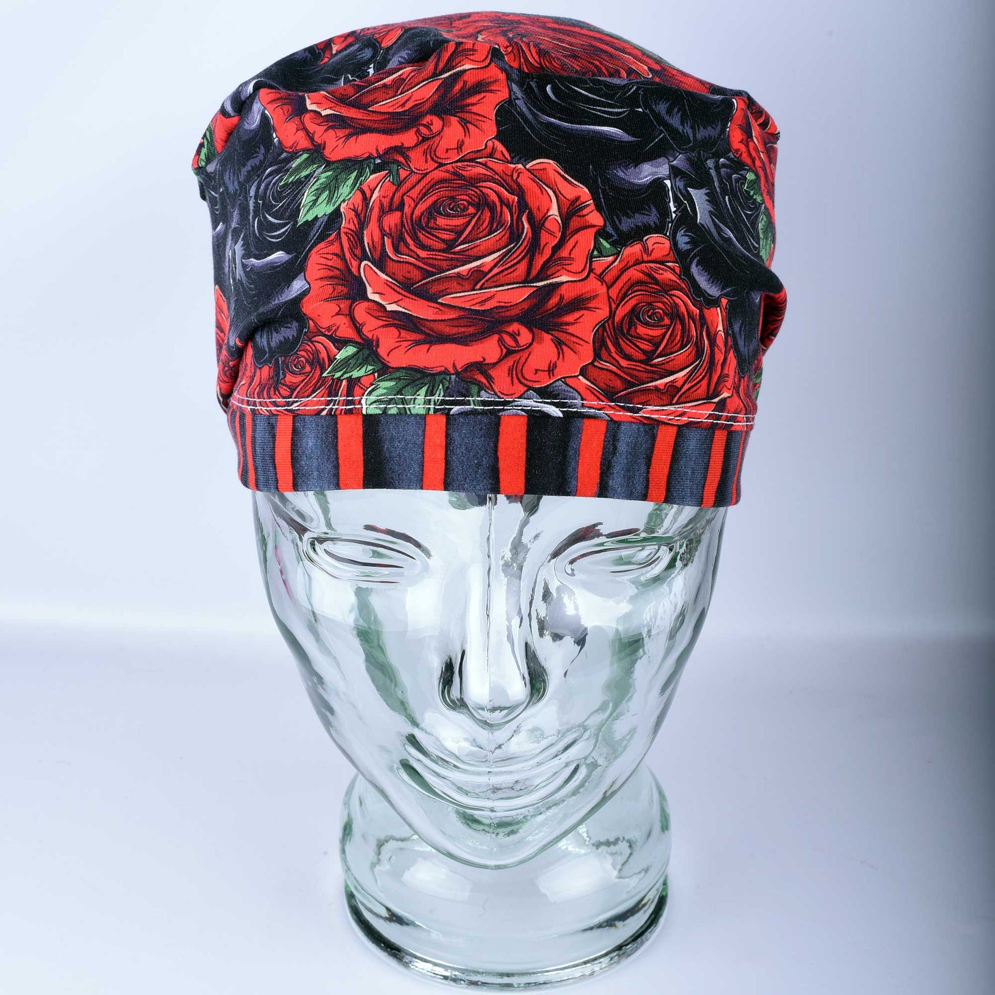 Full coverage scrub cap featuring a vibrant red and black rose floral pattern on a dark background, shown from a side profile to highlight the adjustable fit.