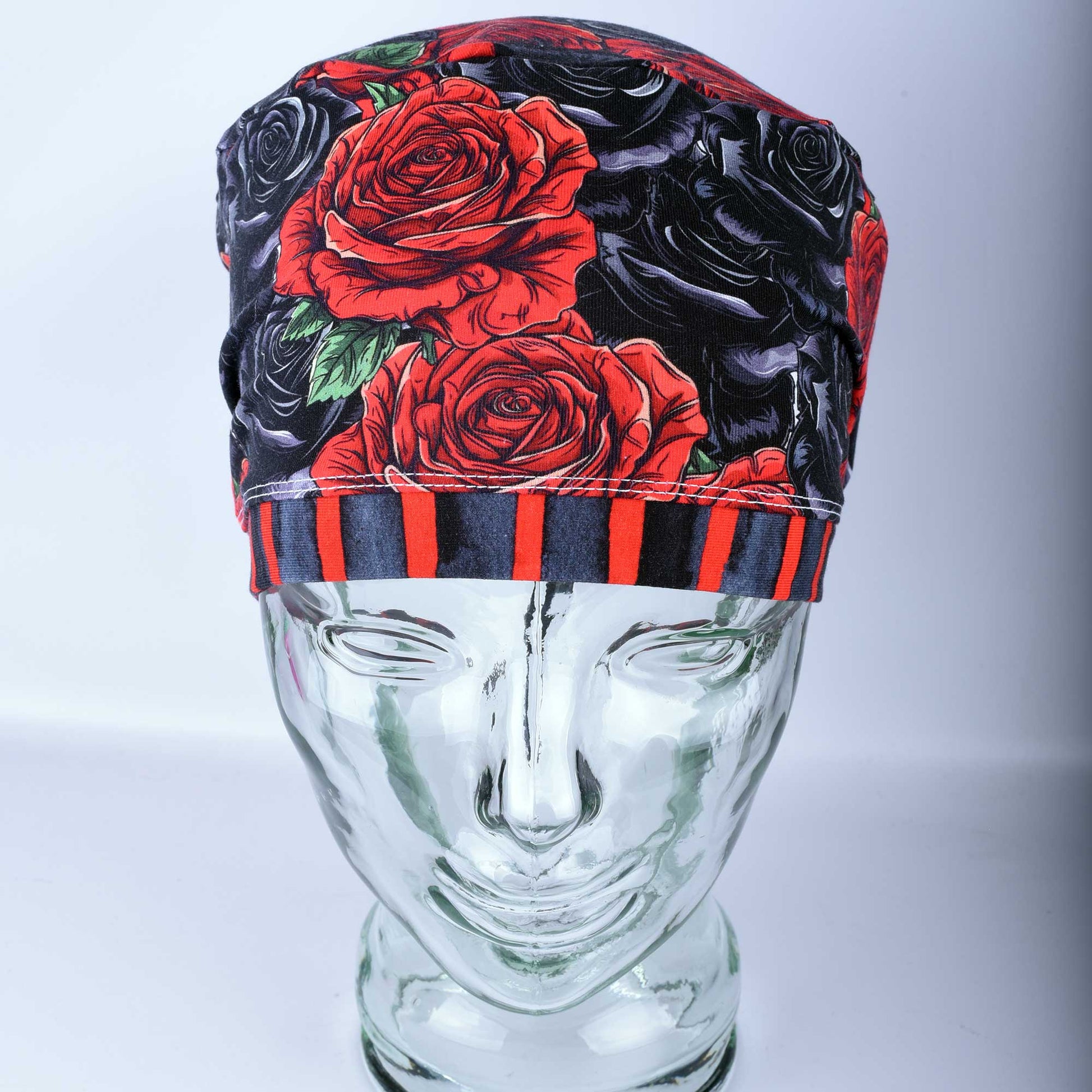 Full coverage scrub cap featuring a vibrant red and black rose floral pattern on a dark background, shown from a side profile to highlight the adjustable fit.