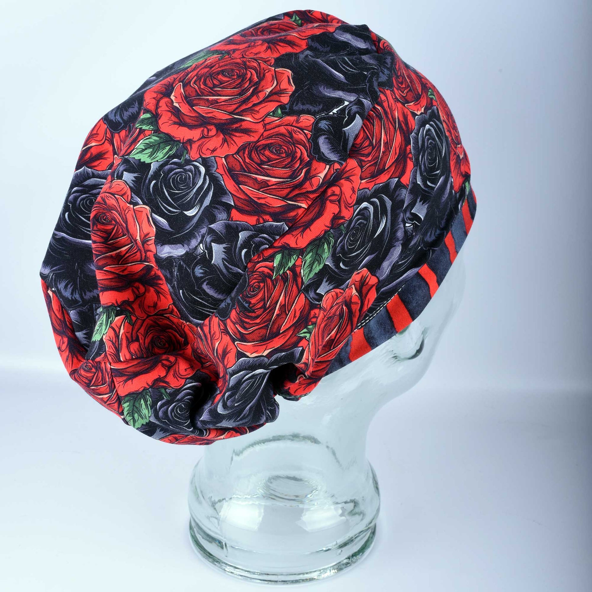Full coverage scrub cap featuring a vibrant red and black rose floral pattern on a dark background, shown from a side profile to highlight the adjustable fit.