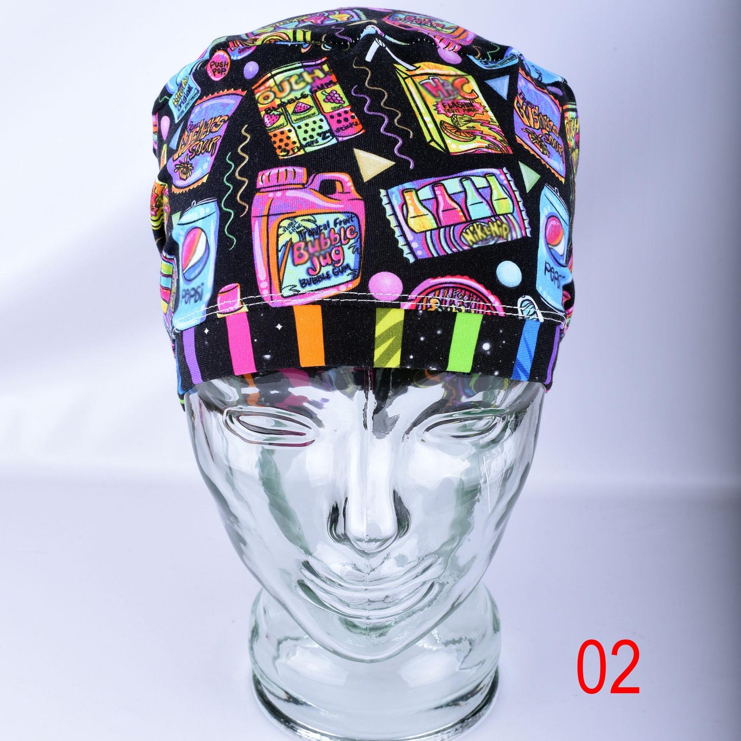 A multicolor retro-themed surgical scrub cap displayed on a clear glass mannequin head. The cap features a black background with a vibrant, colorful pattern of neon-style bubblegum bottles, cassette tapes, and candy.