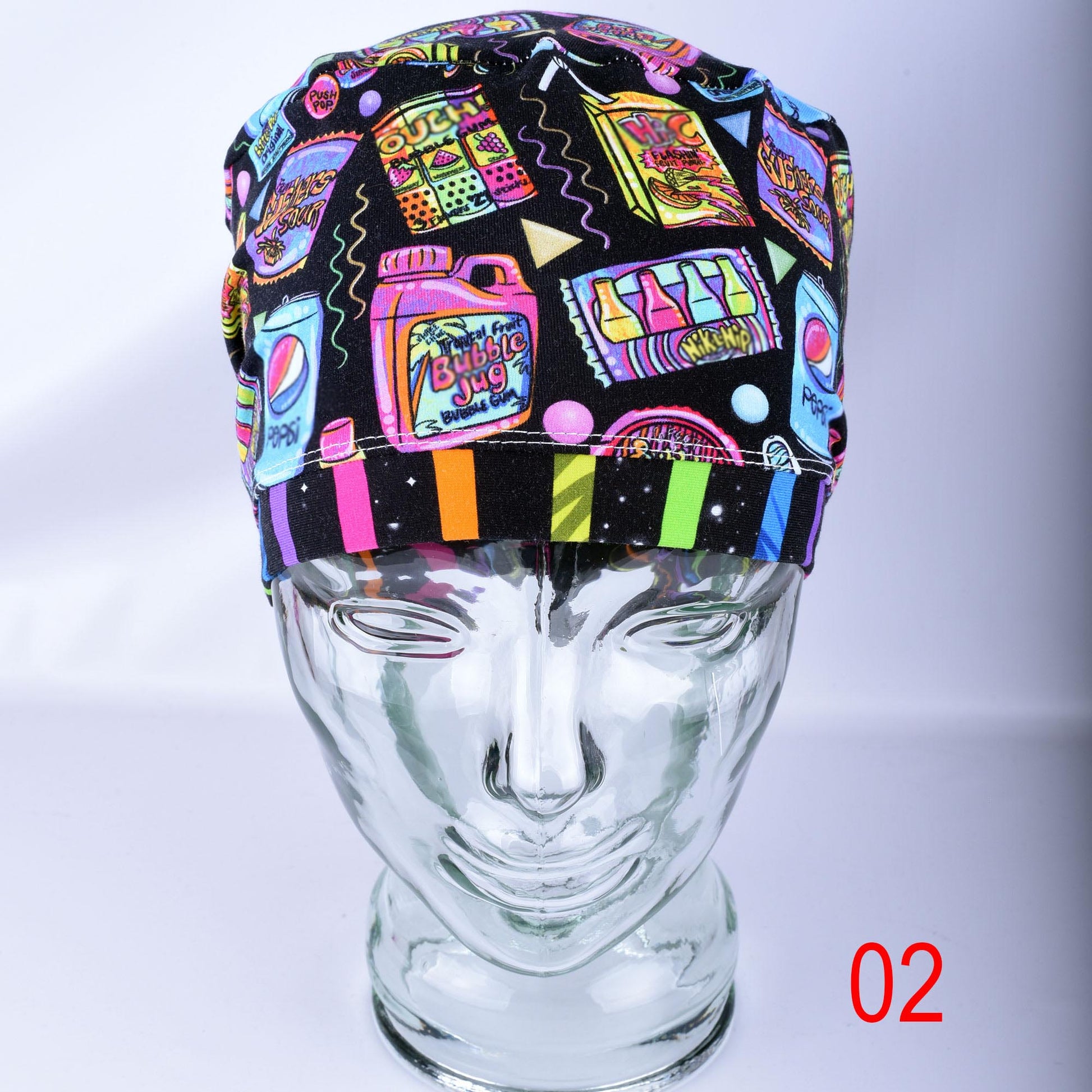 A multicolor retro-themed surgical scrub cap displayed on a clear glass mannequin head. The cap features a black background with a vibrant, colorful pattern of neon-style bubblegum bottles, cassette tapes, and candy.