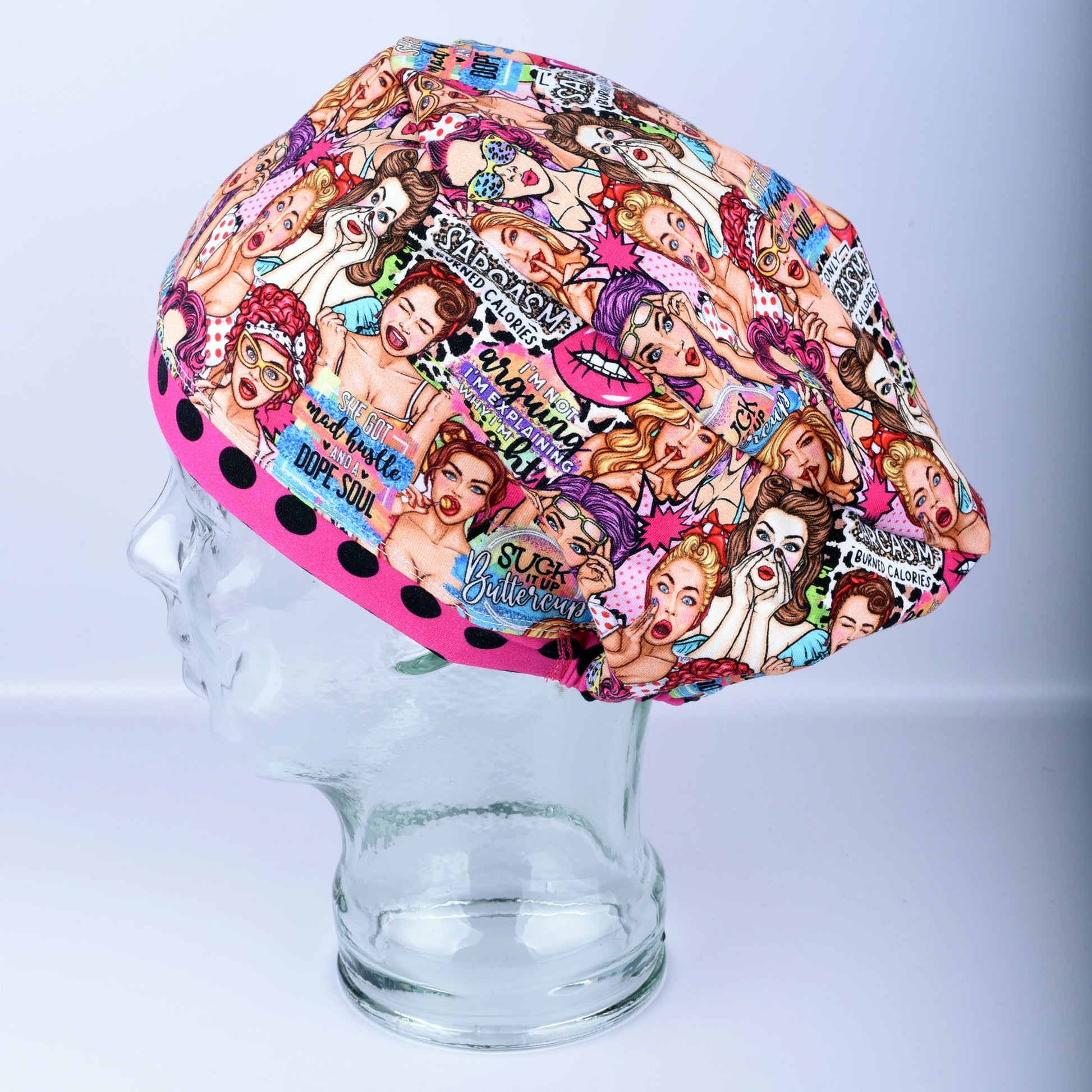 Sassy Women scrub cap with a pink brim on a clear display mannequin head, side view showcasing the colorful retro women artwork pattern.