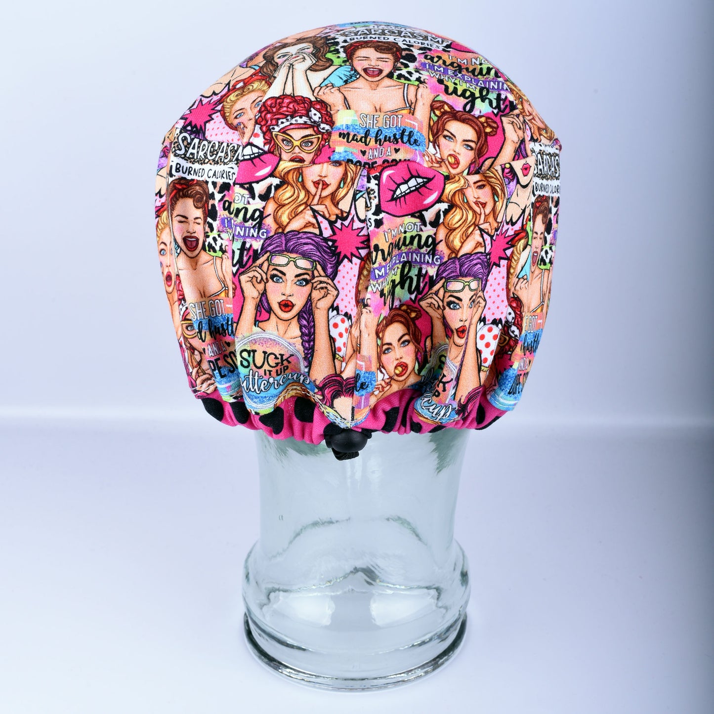 Back view of the Sassy Women scrub cap on a clear display head, showing the encased elastic band and adjustable cord lock toggle for a secure fit.