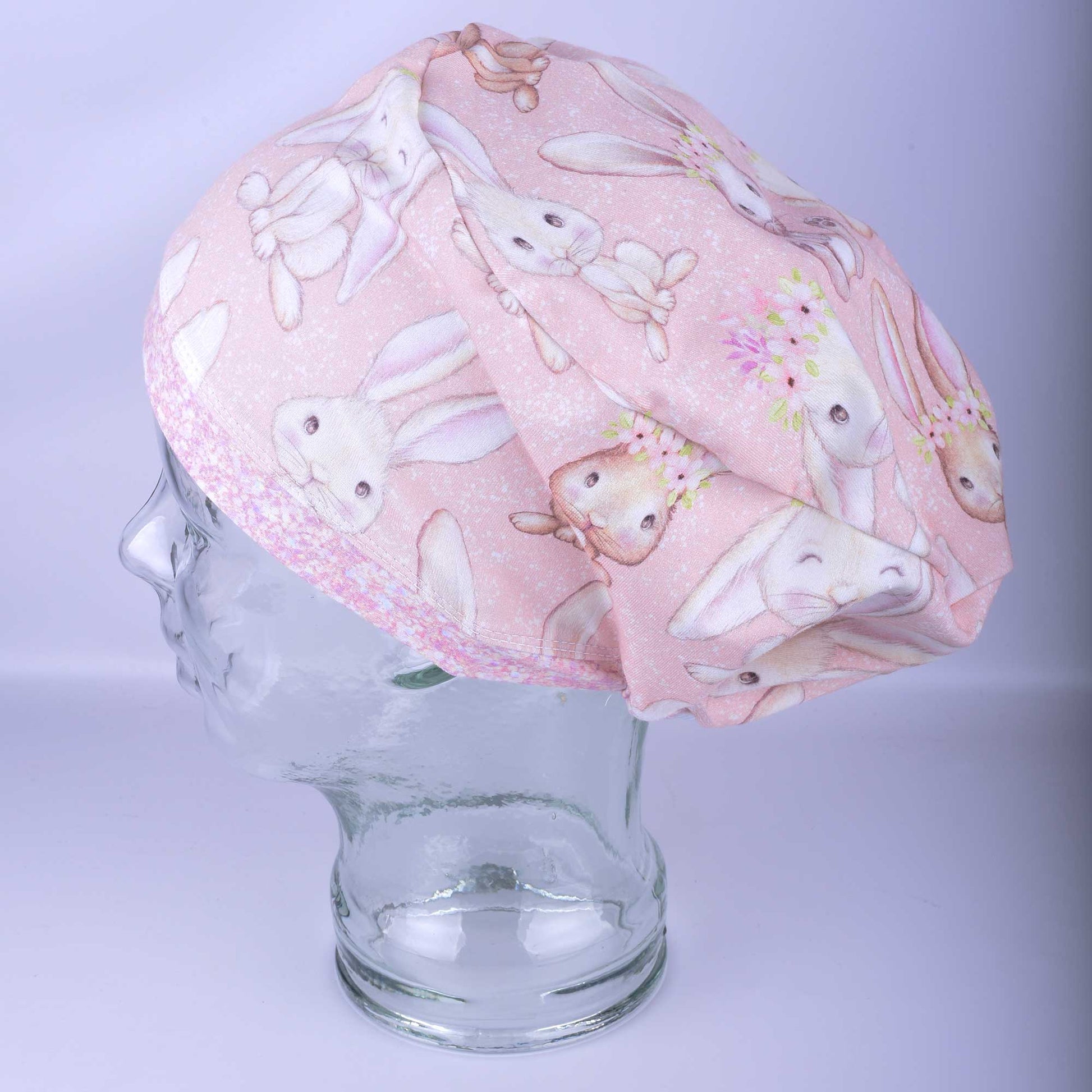 Pink scrub cap with bunny pattern on a mannequin head against a light purple background