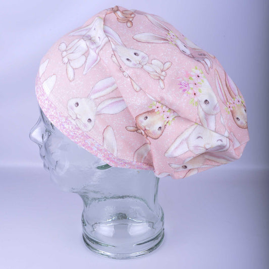 Pink scrub cap with bunny pattern on a mannequin head against a light purple background