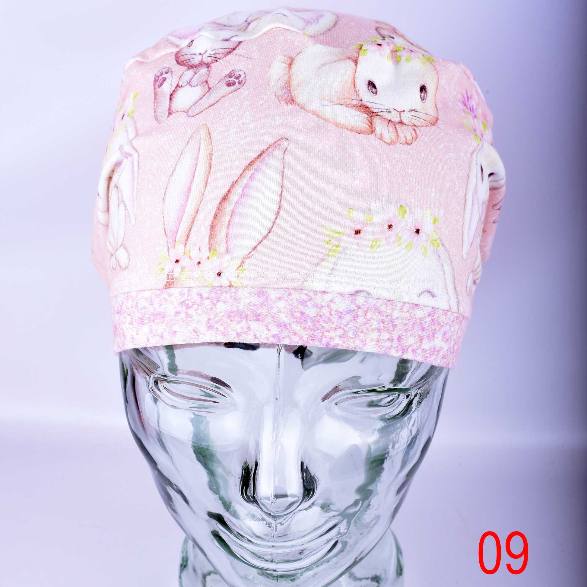 Front angle of the Sweet Bunnies medical scrub cap on a clear mannequin head, highlighting the wide comfort band across the forehead.