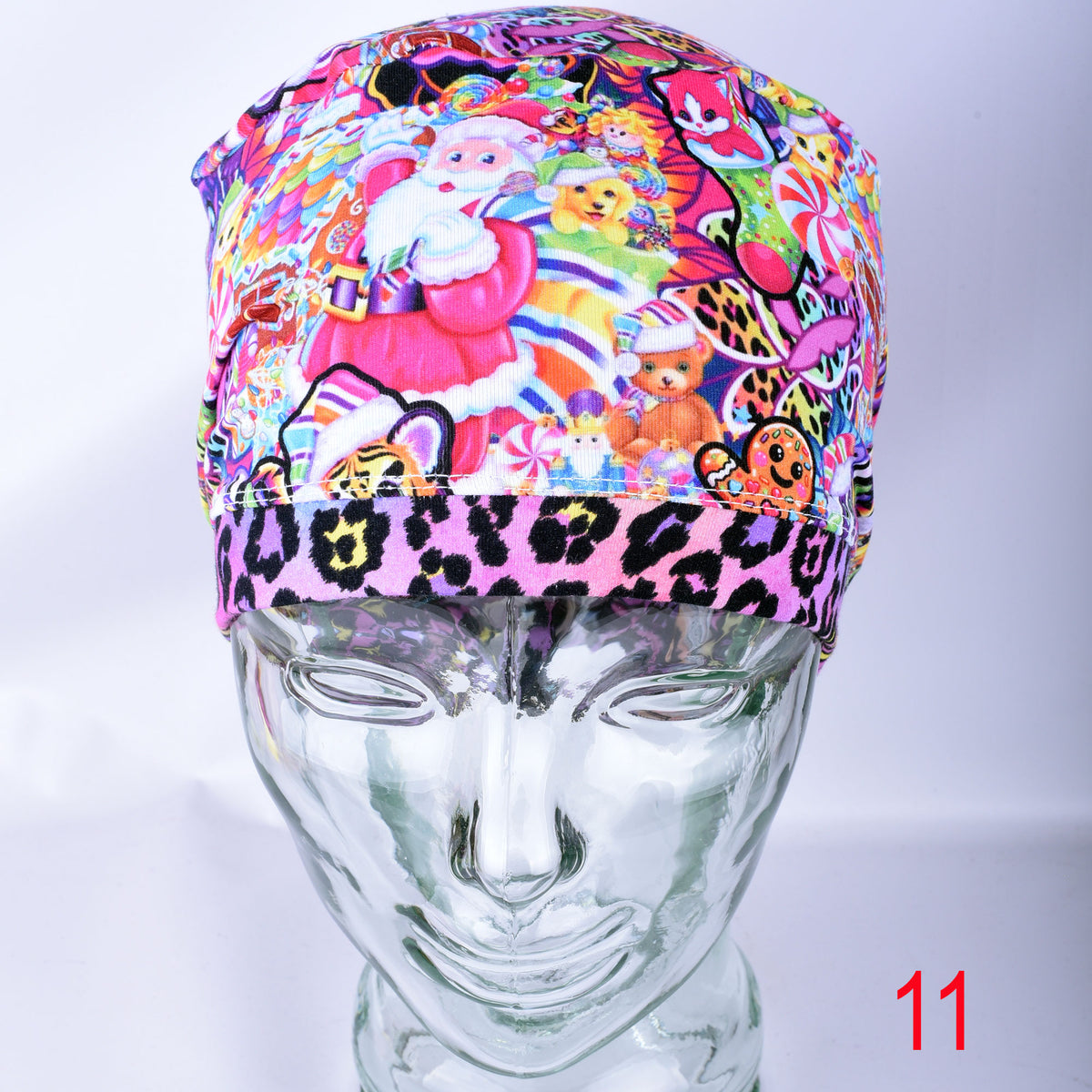 Front view of the Christmas Sweets medical scrub cap on a clear mannequin, showcasing the full-coverage fit and continuous festive holiday treats pattern across the front brim with a red "11" variant marker.
