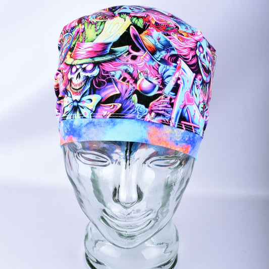 A colorful medical scrub cap with a vibrant, multicolored psychedelic print featuring cartoon skulls, hats, and abstract patterns, displayed on a clear glass mannequin head against a light gray background.