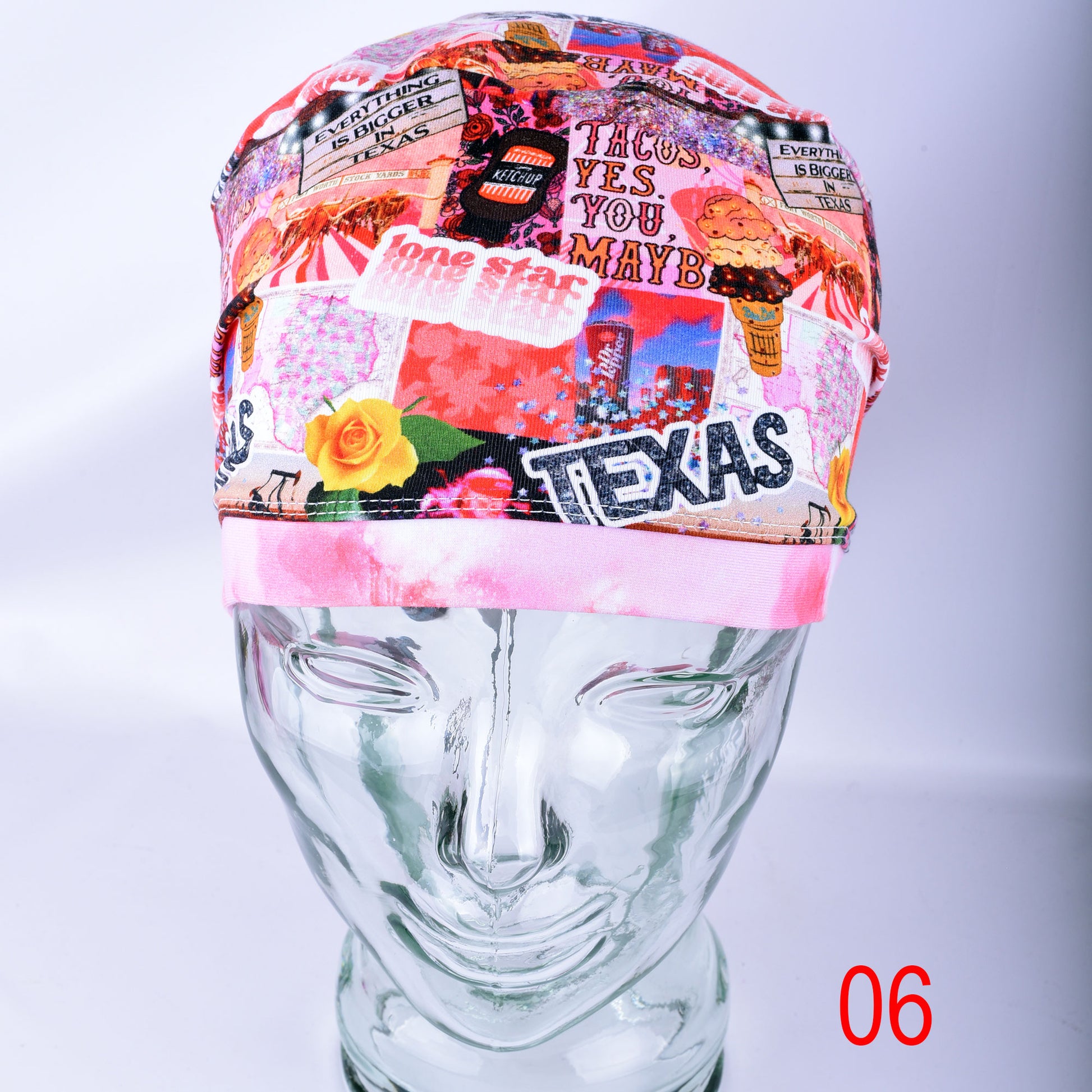 A multicolor collage-patterned surgical cap displayed on a clear glass mannequin head. The pattern features various Texas-themed elements, including the word 'TEXAS', a yellow rose, and a pink band at the bottom.