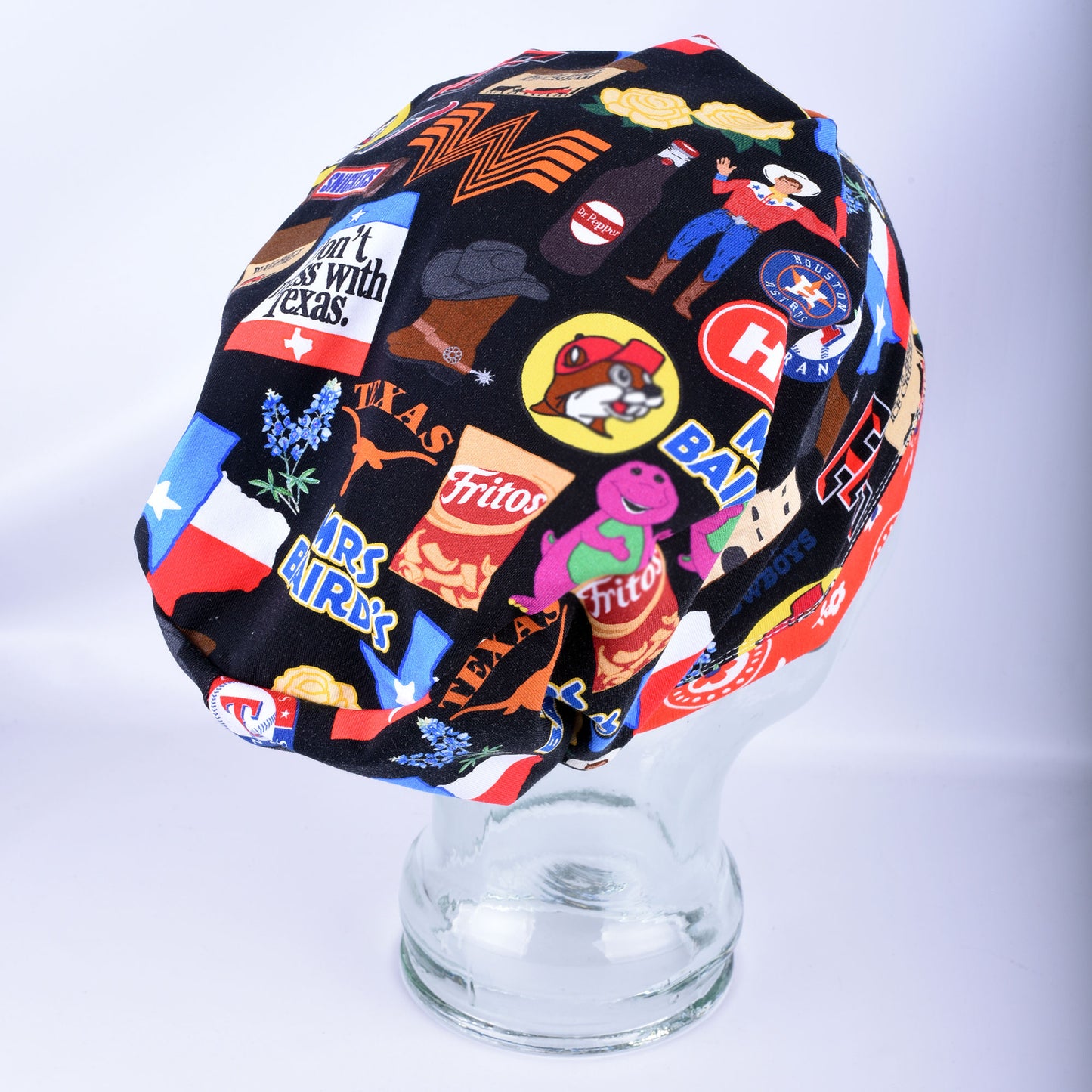 Side view of the Texas Love scrub cap on a clear display head, showing the encased elastic band and adjustable cord lock toggle for a secure fit.