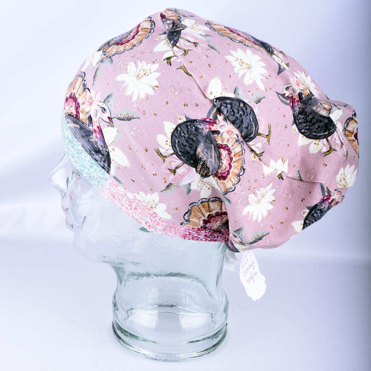 Side view of a Thanksgiving turkey print scrub cap featuring a rear elastic toggle closure on a clear mannequin head.