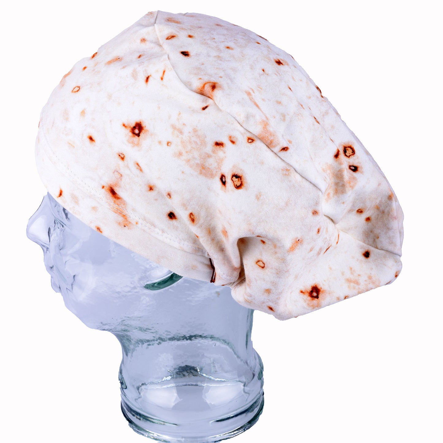 A full coverage scrub cap featuring a realistic flour tortilla print with toasted brown spots, displayed on a white mannequin head.