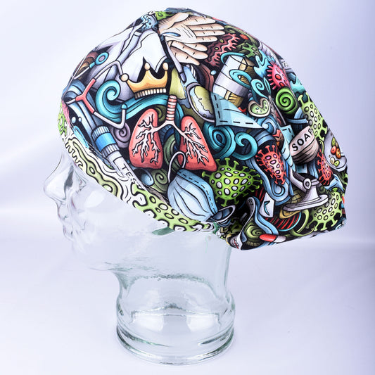 A multicolor medical-themed scrub cap with a detailed cartoon illustration of lungs, a stethoscope, a crown, and other healthcare symbols, displayed on a clear glass mannequin head against a light gray background.
