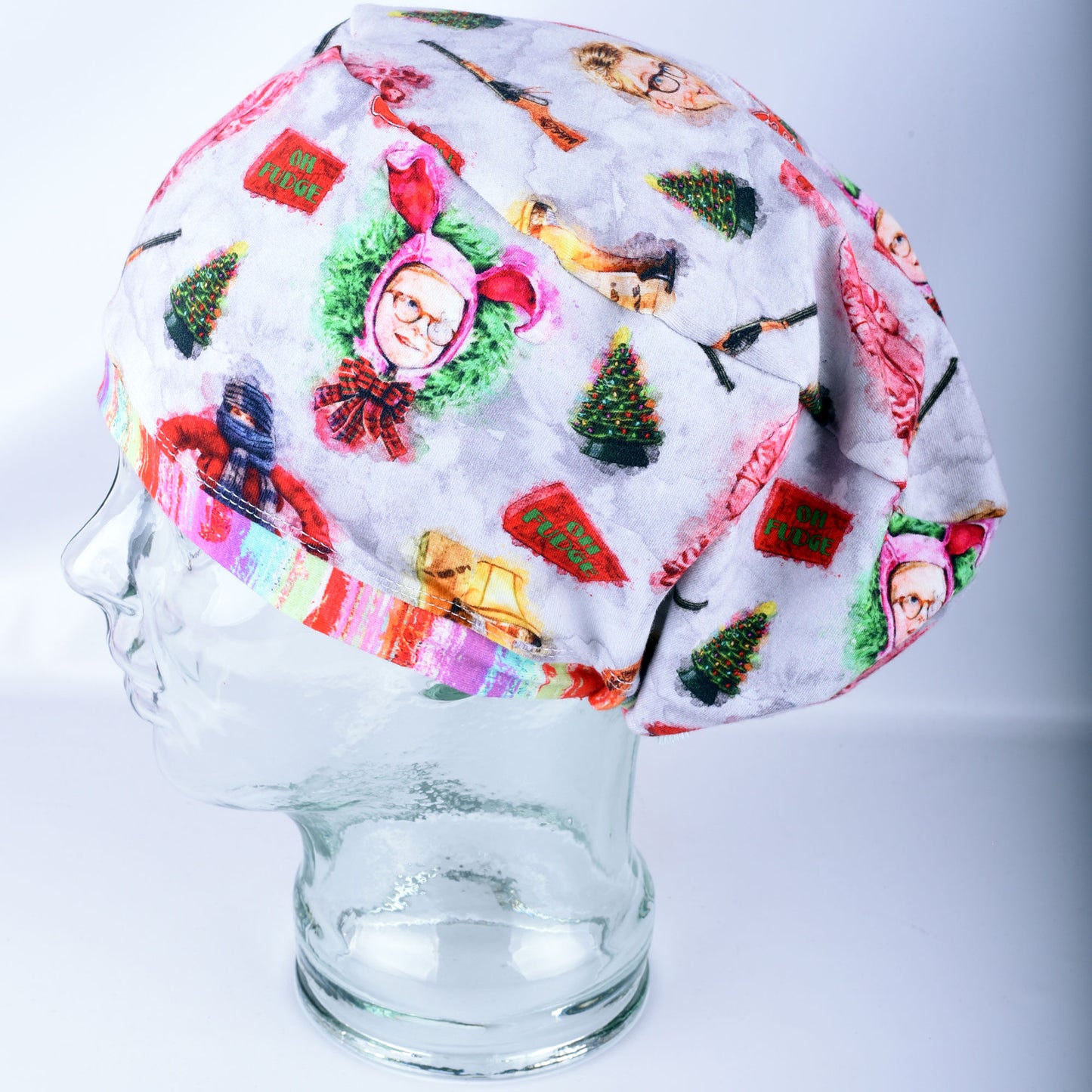 Side angle view of the Watercolor Christmas Euro-style scrub cap on a clear mannequin head, highlighting the soft fabric, precise stitching, and unique holiday pattern placement.