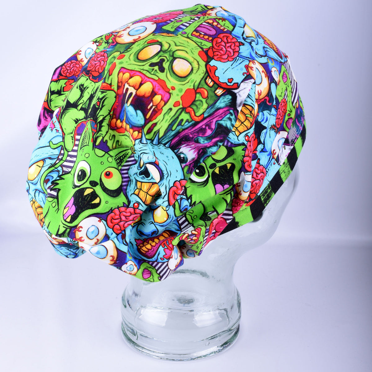 Alternate side view of a full-coverage scrub cap with a vibrant neon zombie pattern and an encased elastic back with a toggle clasp.