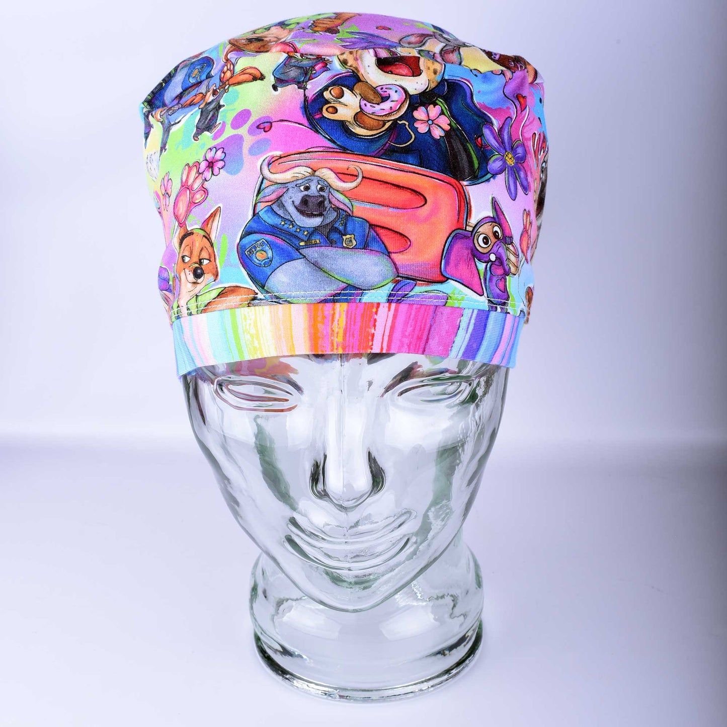 Full coverage scrub cap featuring a "Zoo Friends" pattern with colorful, hand-drawn rabbits, sloths, lions, and sheep on a white background. Includes an adjustable cord lock for a secure fit.