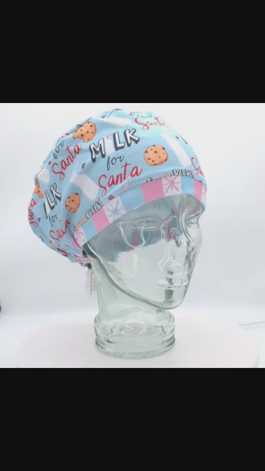 360-degree rotating video of a clear mannequin head displaying a full-coverage scrub cap featuring a light blue festive print with chocolate chip cookies, glass milk bottles, pink accents, and "Milk for Santa" text.