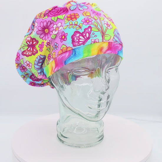 360-degree rotating video of the Butterflies and Flowers Euro-style scrub cap on a clear mannequin head, displaying the colorful floral and butterfly print, adjustable toggle, and full coverage fit.