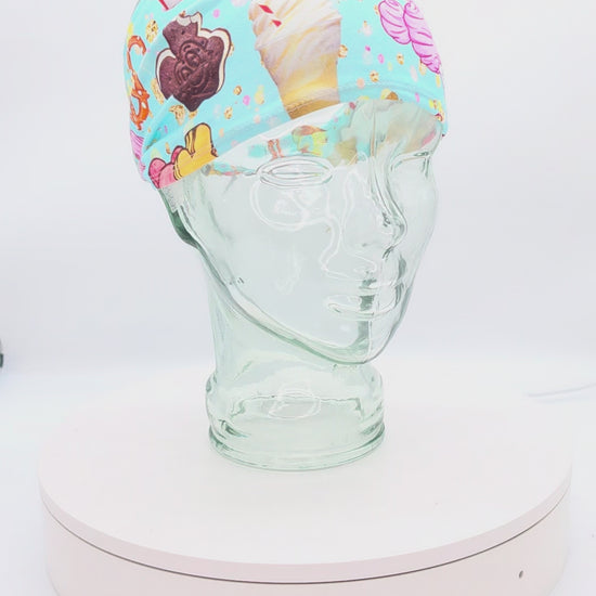 Video showcasing a 360-degree rotating view of the Magical Snacks wide headband on a clear mannequin head, highlighting the vibrant theme park treats pattern and adjustable cord-lock toggle fit.