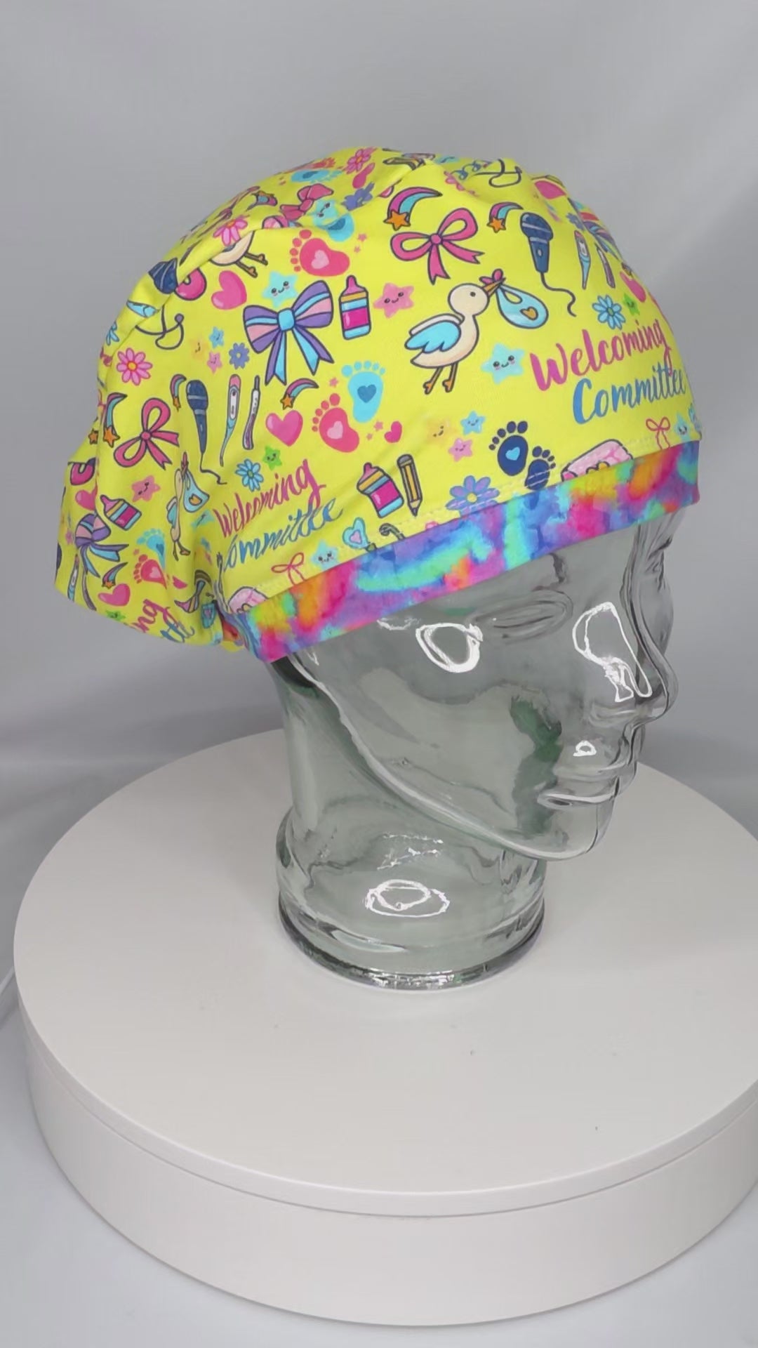 Video preview of the adjustable Welcoming Committee scrub cap rotating on a clear mannequin head, demonstrating the 360-degree fit and custom-milled fabric quality.
