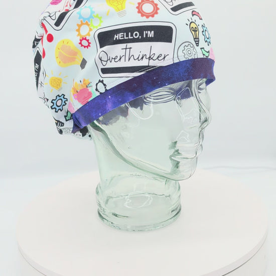 A 360-degree rotating product video showcasing the 'Overthinker' full-coverage scrub cap on a clear display stand, highlighting the colorful comic-book style graphics, 'Hello, I'm Overthinker' name tag badge illustration, and the secure, snug fit around the brim.