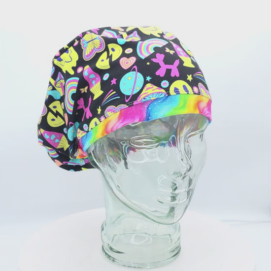 A 360-degree rotating video showcasing the Retro Days Scrub Cap on a clear mannequin head. This Euro-style medical hat features a vibrant, nostalgic 70s throwback print on a black fabric background filled with colorful smiley faces, rainbows, mushrooms, peace signs, and butterflies, accented by a rainbow swirl front brim.