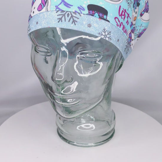 A demonstration video showing the high-quality stretch, adjustable drawstring toggle, and comfortable fit of the "Let it Snow" snowman scrub cap.