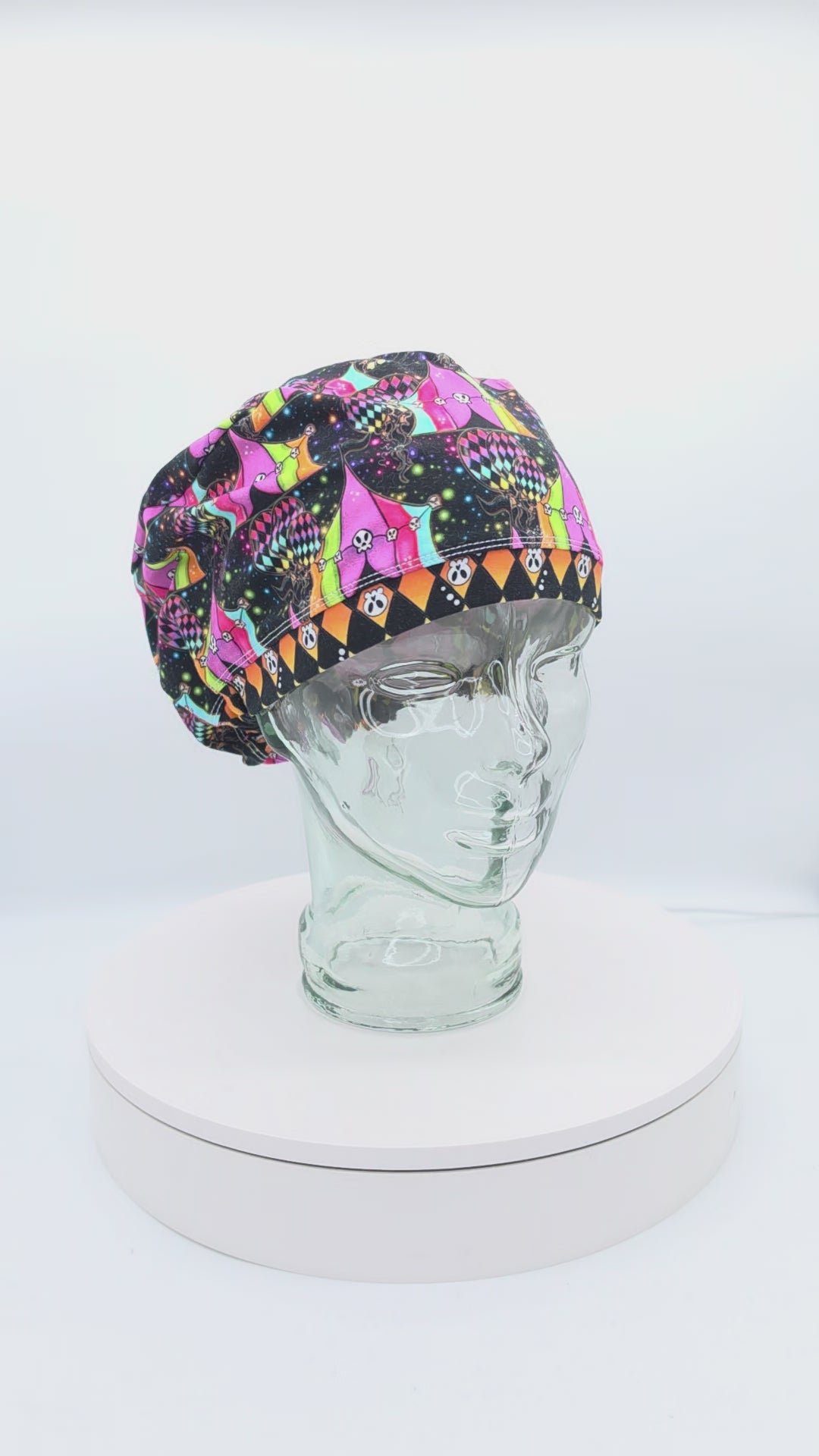 360-degree rotating video of a Spooky Carnival full coverage scrub cap on a display head, highlighting the neon carnival print and rear adjustable toggle.